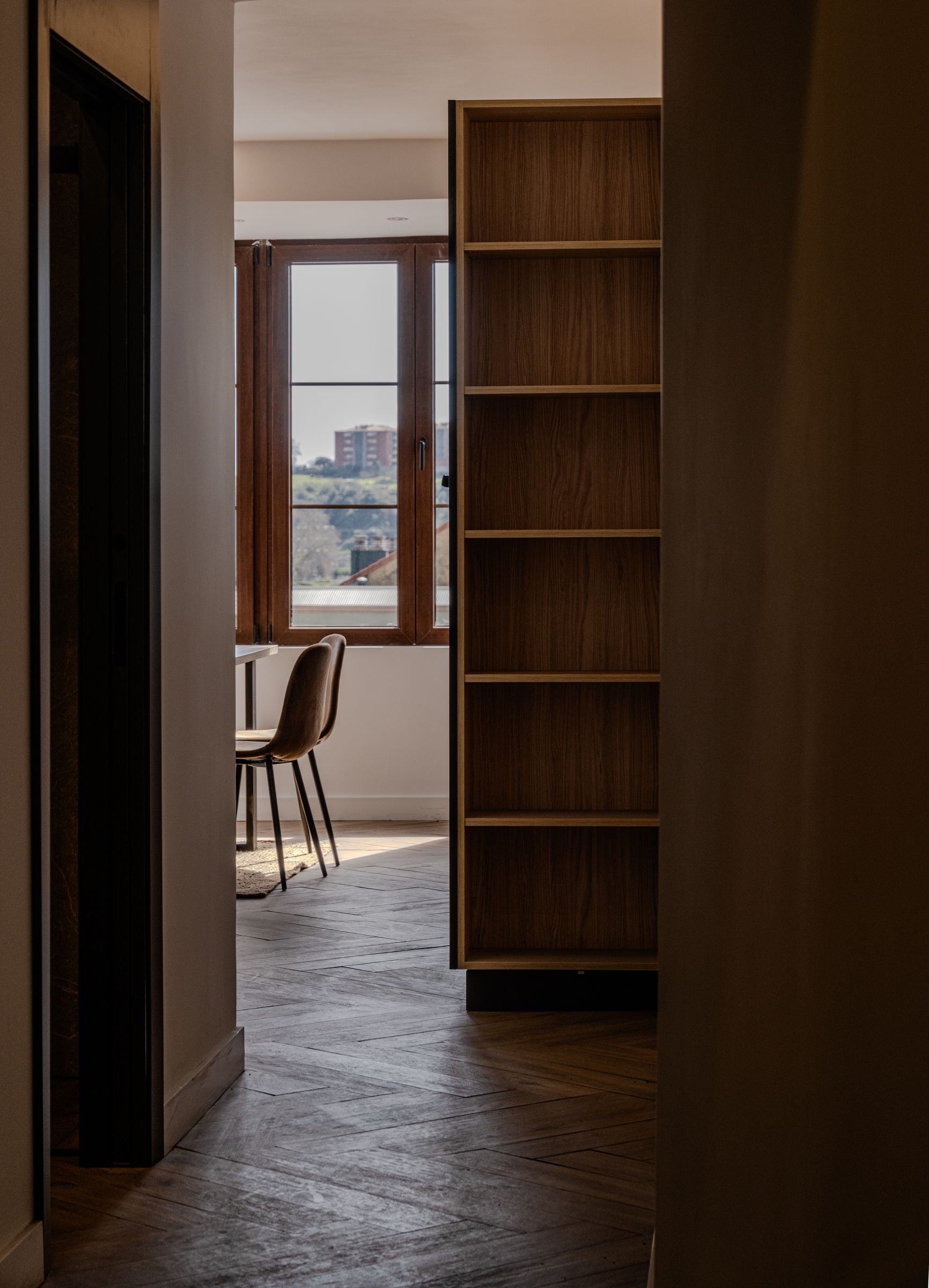 Pasillo con estantería de madera a medida y suelo en espiga