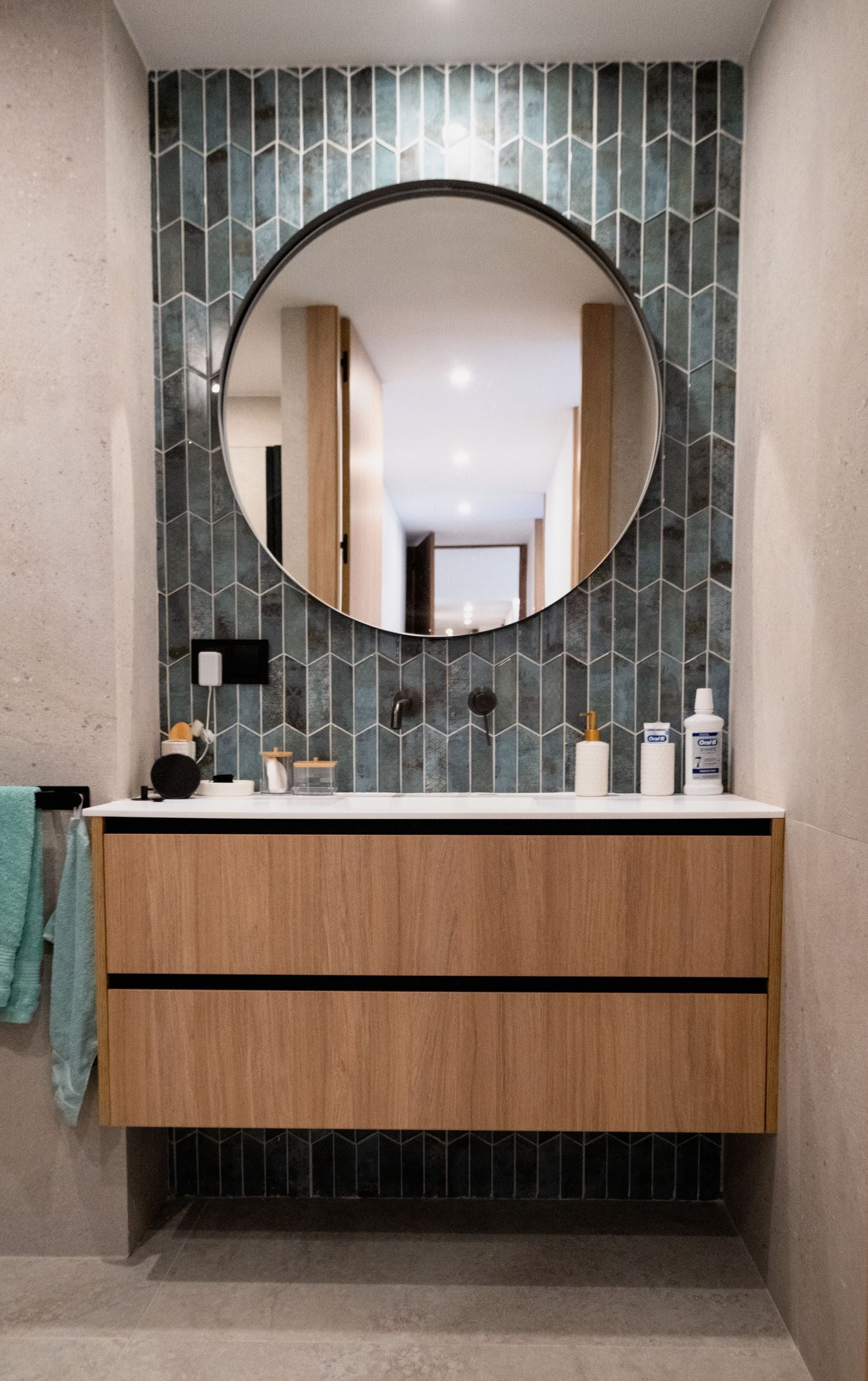 Lavabo con azulejo verde en espiga y espejo redondo