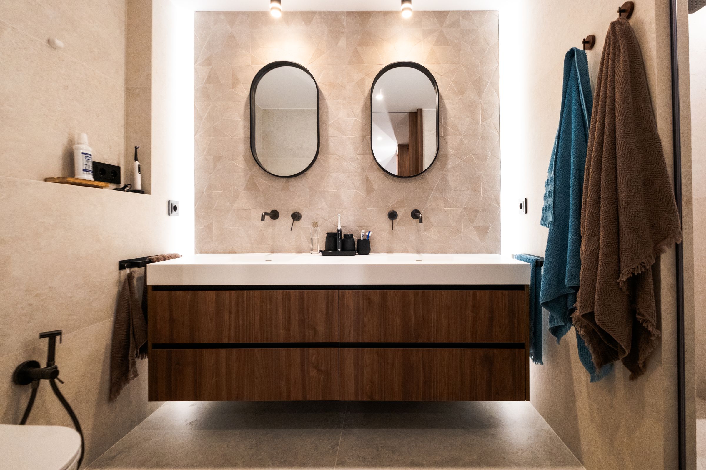 Baño con doble espejo ovalado y mueble de madera suspendido
